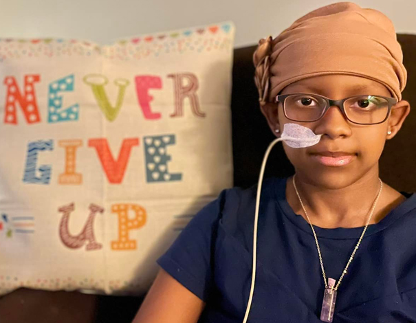 Amelia sits next to her 'Never Give Up' pillow